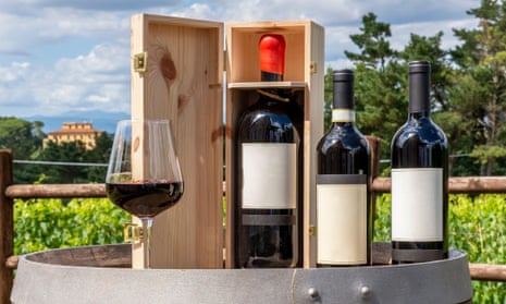 Three bottles including a magnum in the wooden box and a glass of red wine on a wooden barrel
