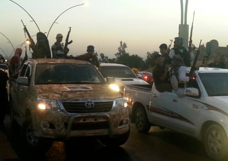 Isis fighters celebrate while sitting on vehicles in the city of Mosul, 23 June 2014.
