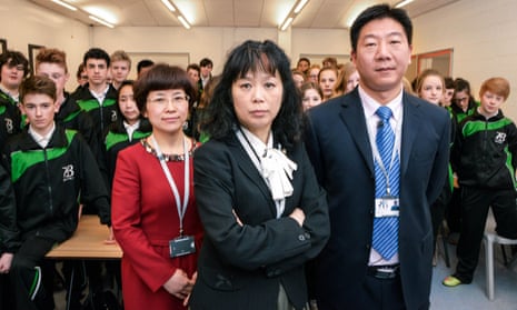 Shot from the BBC's TV programme Are Our Kids Tough Enough? Chinese School showing three teachers (left to right Li Aiyun, Jun Yang-Williams, Hailian Zou) standing in front of a classroom of pupils