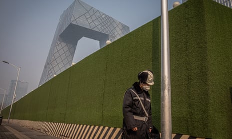 A worker wearing a protective face mask walks next to a construction site in Beijing.