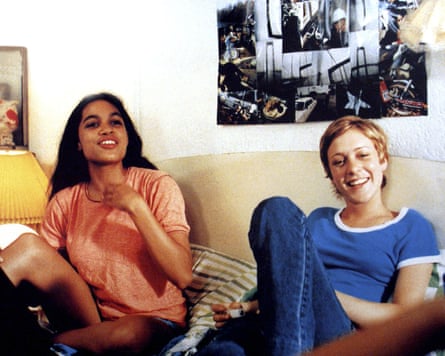 Rosario Dawson and Chloë Sevigny smiling while sitting on a sofa in the film Kids