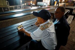 Two people watch on a phone as president Cyril Ramaphosa announces lockdown measures to restrict the spread of coronavirus in South Africa