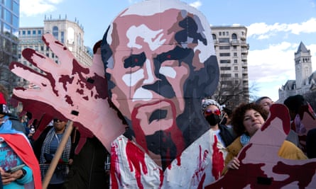 Une grande découpe en carton peint de Joe Biden avec du sang sur les mains et sortant de la bouche, les yeux rouges.