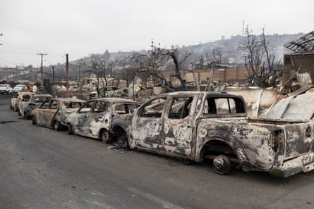 The remains of burned cars are lined up on a street