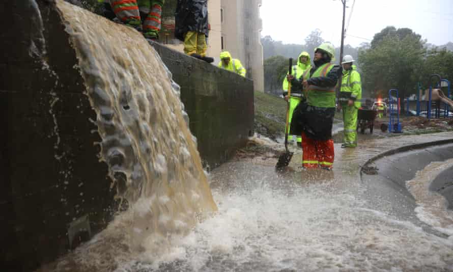 Workers try to divert water into drains as rain pours down in Marin City, California.