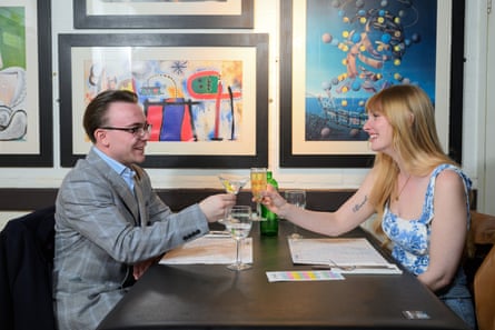 Callum and Emma clinking their glasses across a restaurant table