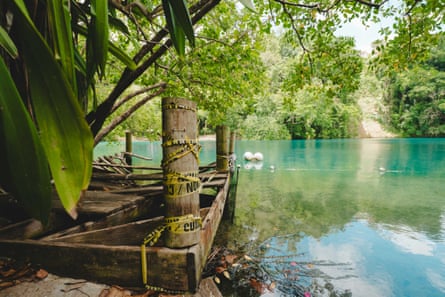 A damaged dock is shown on a blue lagoon surrounded by trees.
