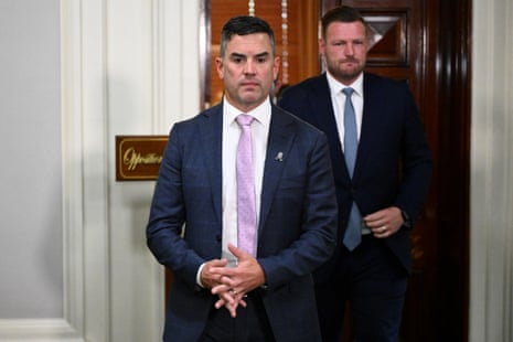 A man in a dark suit and pink tie.