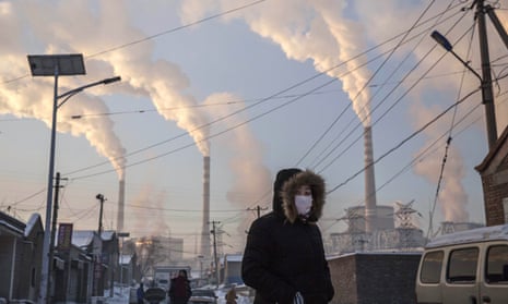 A woman walks past a coal-fired power plant in Shanxi, China. 