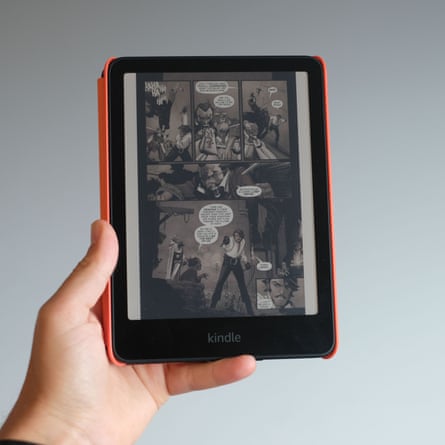 A hand holds a Kindle e-reader displaying a dark comic book page with speech bubbles