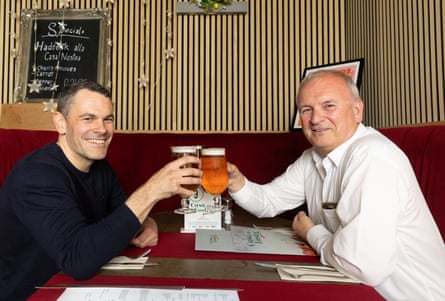 Martyn and Alan clinking glasses across a restaurant table