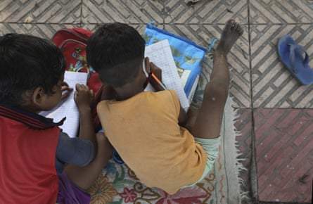 Children practice writing numbers during a street class three times a week in Delhi, India.