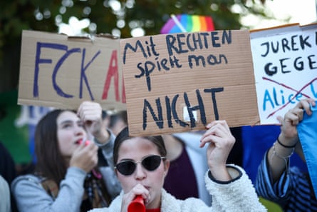 Several people hold up handmade placards in German