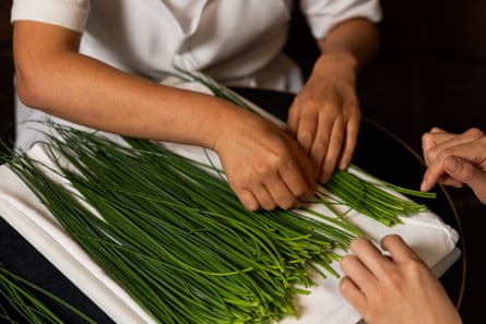 Trisha picks through a large bundle of chives to remove any bruised, wilted, slimy or pale specimens