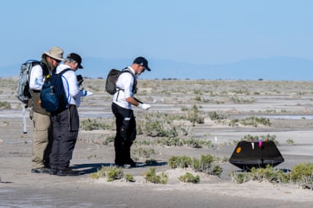 Nasa scientists collect data next to the sample return capsule from Osiris-Rex mission after landing at the Department of Defense’s Utah Test and Training Range on Sunday.