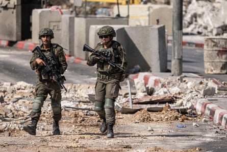 Israeli soldiers patrol a rubble-strewn street in Hebron, West Bank