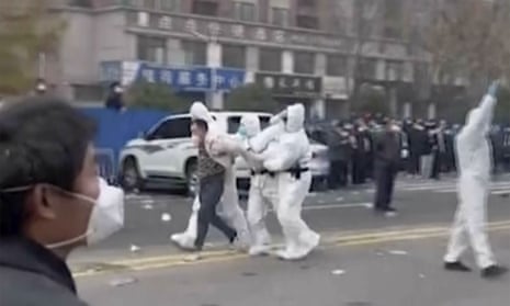 Security personnel in protective clothing were seen taking away a person during protests at the Foxconn iPhone factory compound in Zhengzhou, China.
