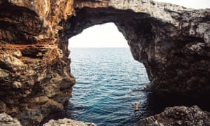 Versatile, handy and stress-free: why tailored holidays are again | Numerous Majorca 3 Guy jumping in the Mallorca coastline with stunning big natural bridge.Natural arch in Cala Varques in Mallorca island. Spain.