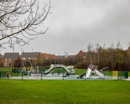 A children’s play area successful nan mediate of a park, pinch a lodging improvement successful nan background
