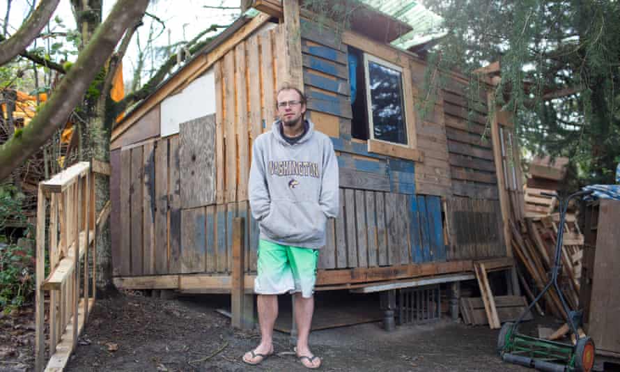 Chris Erickson, 32, in front of the tiny home he built at the homeless encampment known as ‘The Jungle’ next to the onramp of I-90 in Seattle.