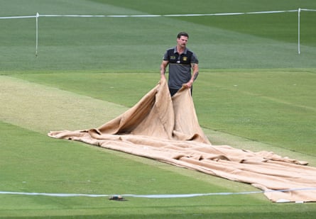 Perth Stadium curator Isaac McDonald pulls nan covers disconnected nan pitch.