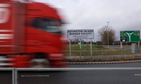 A lorry drives on a road past a sign reading 'Sevington Inland Border Facility'