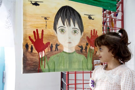 A girl looks at a painting depicting a Palestinian child traumatized by war during an art exhibition in Sana’a, Yemen.