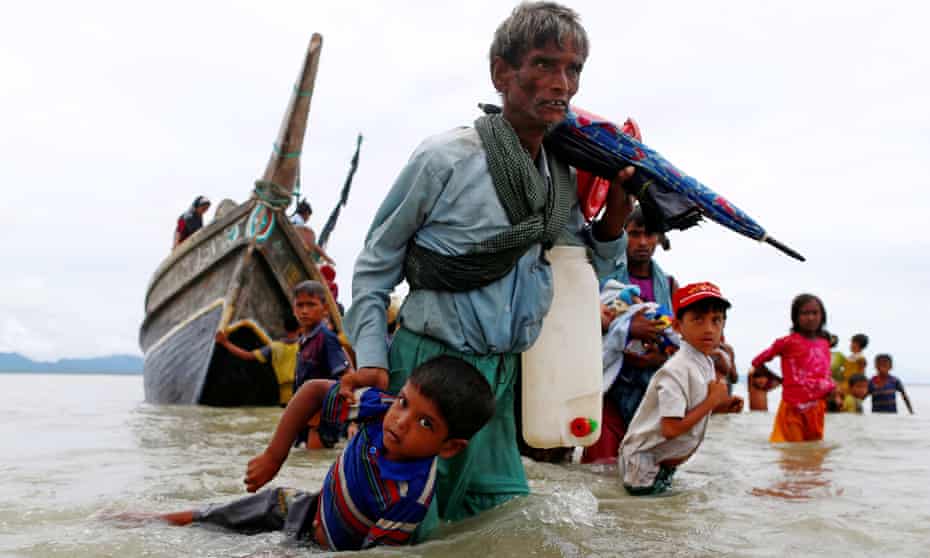 A Rohingya refugee pulls a child as they walk to the shore after crossing the Bangladesh-Myanmar border by boat on Sunday.