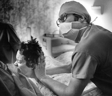 health worker holds up head of woman in distress on bed