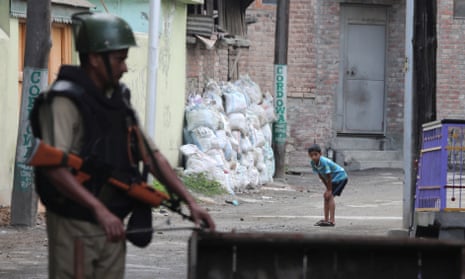A Kashmiri child sees an Indian paramilitary soldier erecting a barricade in Srinagar.
