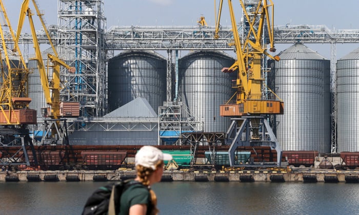 A woman walking past grain silos in Odesa