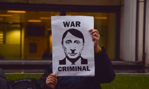 Russia-Ukraine war latest: No casualty toll yet after Russian bombardment of Mariupol theatre, says official – live 2 A protester holds a sign comparing Putin to Hitler and calling him a ‘war criminal’ in London