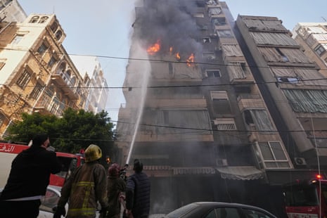 मध्य बेरूत में इजरायली हवाई हमले के बाद अग्निशामकों ने जलती हुई आवासीय इमारत पर पानी का छिड़काव किया