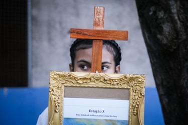 Image 25: A young girl looks from behind a cross