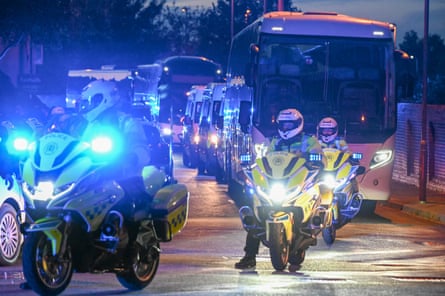 Police on foot, in vans and on bikes provide escort to coaches at dusk.