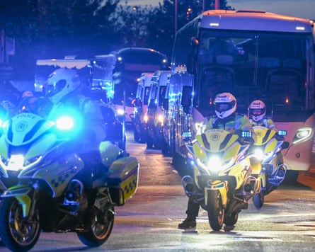 Police on foot, in vans and on bikes provide escort to coaches at dusk.