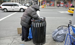 Homeless person searching through rubbish bin on New York city street