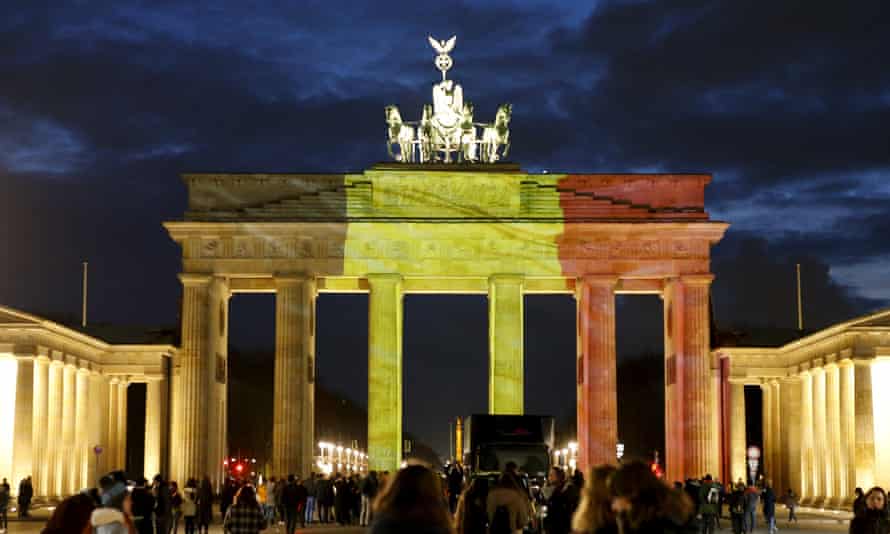 People stand in front of the Brandenburg gate, which is illuminated in black, yellow and red in the colours of the Belgian flag in tribute to victims of Tuesday’s attacks in Brussels in Berlin.