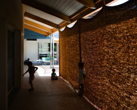 Screened shady area of playground with children behind it