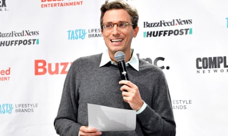 Jonah Peretti talking into a mic on stage in front of the BuzzFeed and Huffpost logos