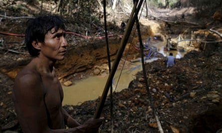 Un homme Yanomami se tient près d'une mine d'or illégale.