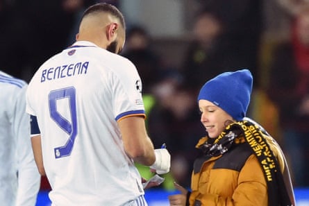 Karim Benzema signs an autograph for a young fan who ran on to the pitch in Moldova.