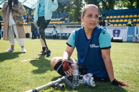 Amputee footballer Tetiana Matseshyna sits on the pitch drinking a bottle of water