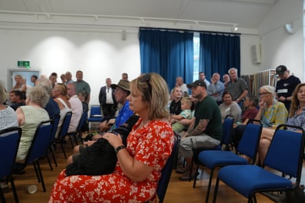 Evacuated residents sit and stand in a hall
