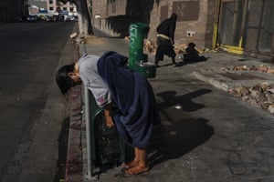 A homeless woman leans on a rail after wetting her hair at a drinking fountain in the Skid Row area of Los Angeles, US