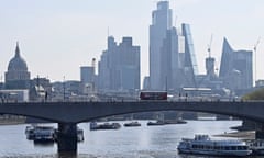 Boats anchored in the River Thames, with buildings in the City of London financial district behind them