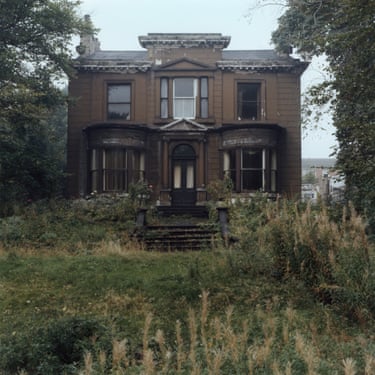An abandoned Victorian mansion in Leeds, overgrown with tall weeds and decaying facade