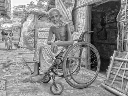 A black and white picture showing a man sitting in a wheelchair in a refugee camp.