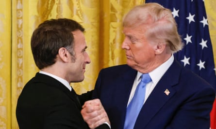 Donald Trump, right, grasps the hand and shoulder of Emmanuel Macron.