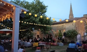 Garden with fairy lights, stage and people drinking